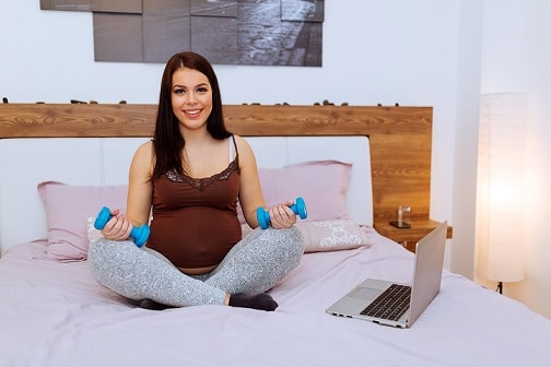 Beautiful pregnant woman exercising at home and working out